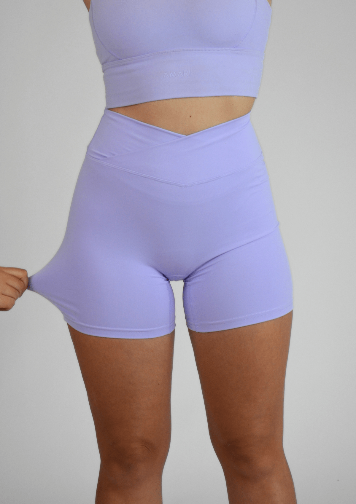 Person wearing light purple athletic shorts and top on a plain background