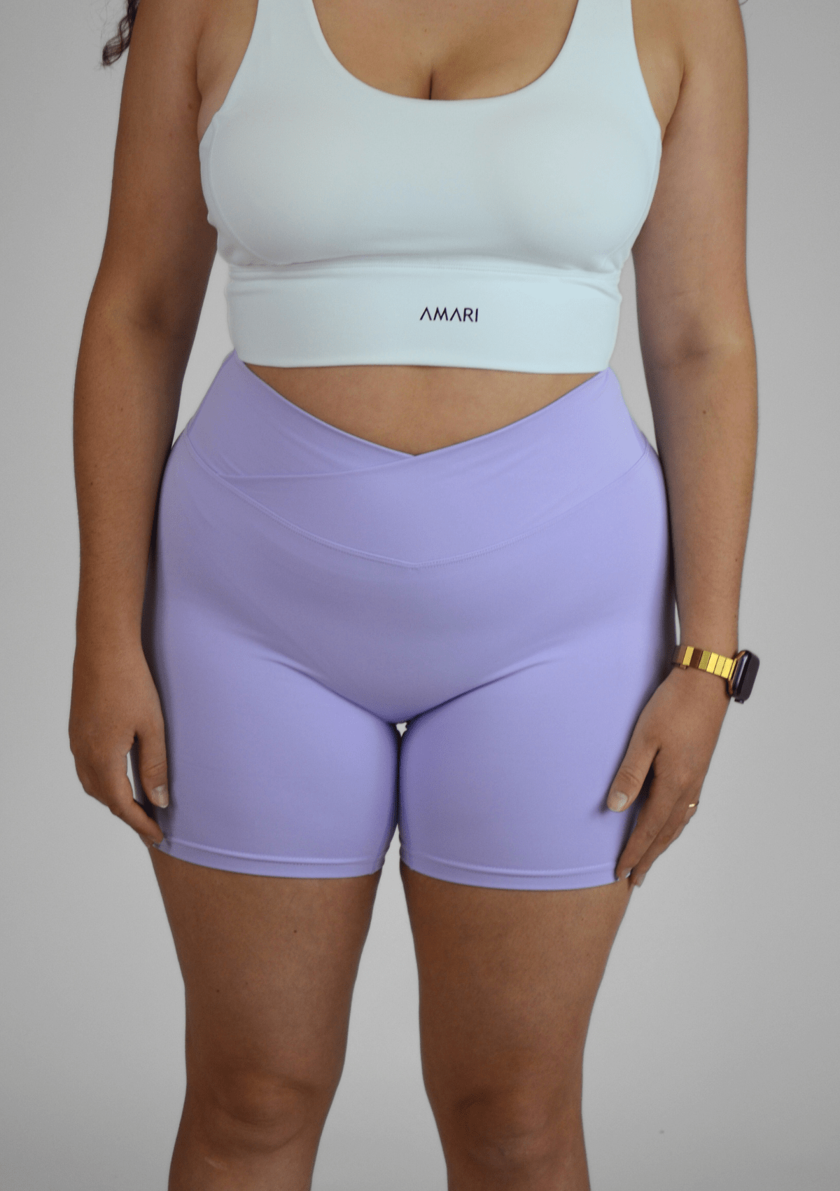 Person wearing a white sports bra and purple shorts on a plain background